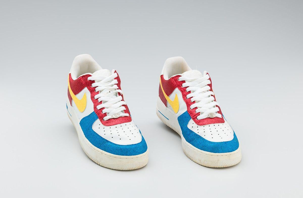 Red, white, yellow, and blue Nike sneakers worn by Big Boi of Outkast, 2005-2006. The shoes feature a bold color-blocking design with a yellow Nike swoosh on the sides. They are part of the National Museum of African American History and Culture collection.